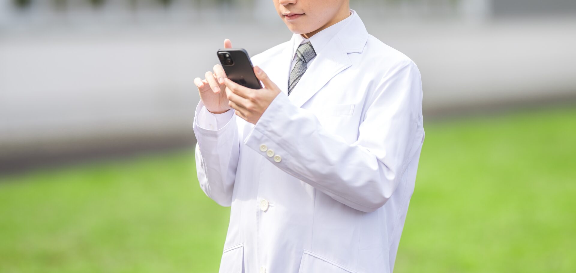 病院の前でスマホを見つめる医師